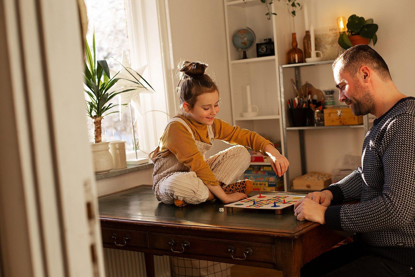 A child and parent playing a board game together at home